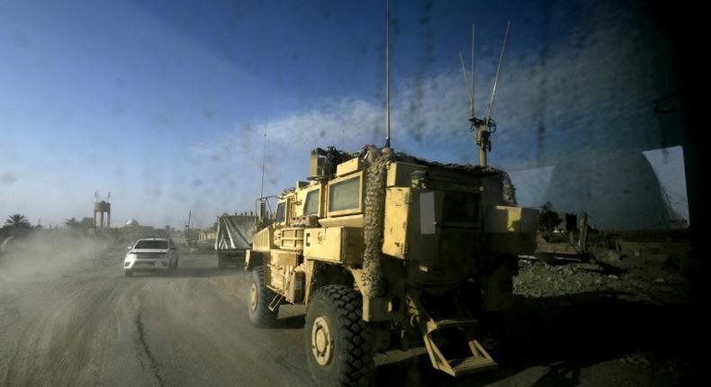 A picture taken from inside a car shows US-led coalition vehicles driving through the Syrian village of Baghouz on January 26, 2019