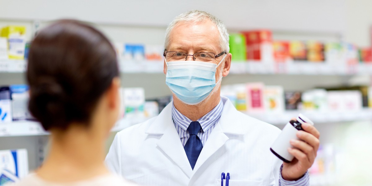 apothecary in mask with drug and woman at pharmacy