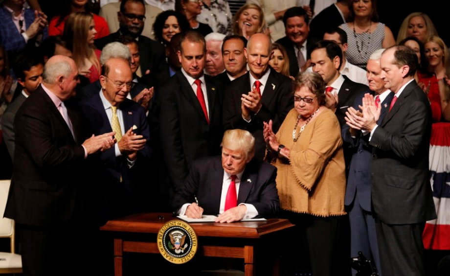 President Donald Trump signs a document after announcing his Cuba policy at the Manuel Artime Theater in the Little Havana neighborhood of Miami, June 16, 2017.