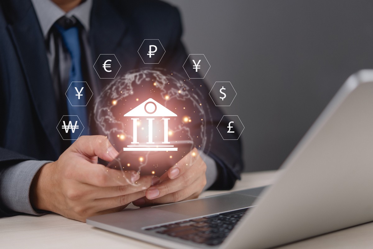 Businessman,Holding,Smartphone,With,Global,Banking,Icons,And,Currency,Symbols.