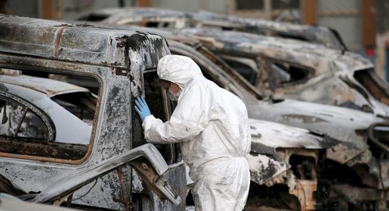 A French police officer inspects burned vehicles outside the Splendid Hotel in Ouagadougou, Burkina Faso, file. 