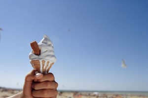 Man holding ice cream on beach, close-up of hand