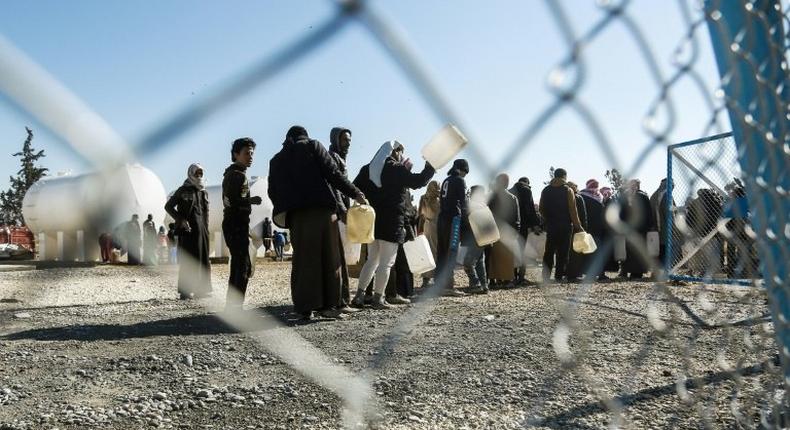 Refugees queue for heating fuel at a UN refugee camp in Syria's Hasakeh province on January 29, 2017