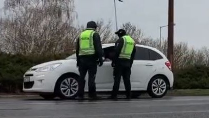 Policajná hliadka kontroluje vozidlá na ceste. 