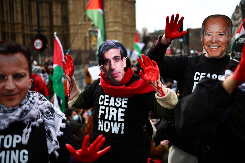 Demonstranci w maskach z twarzami Davida Camerona, Rishiego Sunaka i Joego Bidena na proteście wzywającym do zawieszenia broni w Strefie Gazy, styczeń 2024 r.