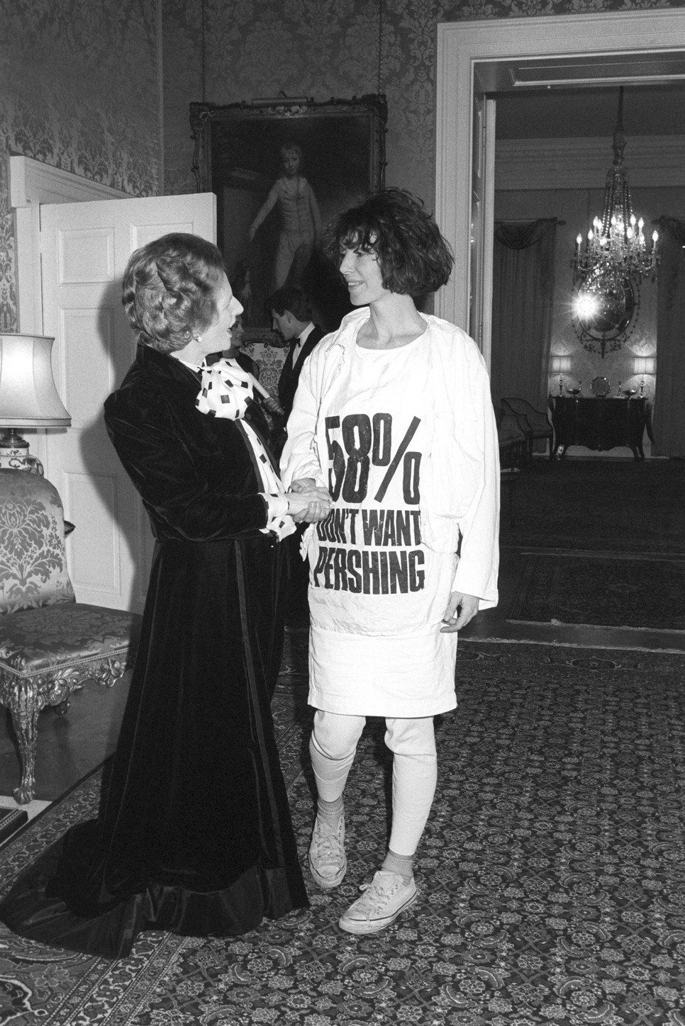 Katharine Hamnett 1984-ben hatalmas botrányt okozott azzal, hogy egy rakétatelepítés ellen tiltakozó pólóban rázott kezett Margaret Thatcher miniszterelnökkel, és ezzel a politikust egy saját politikája ellen tiltakozó performansz részévé tette, és másnap az összes újság címlapján ott volt az üzenet: az választók 58%-a nem akarja a rakétatelepítést, annak ellenére, hogy történik