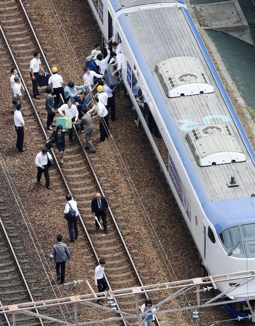 Employees try to remove bottles and cans of beverages which are scattered by an earthquake at a liqu