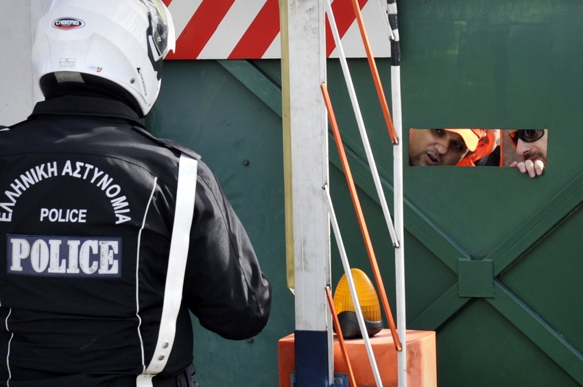 Policajac razgovara sa štrajkačima preko metalne ograde