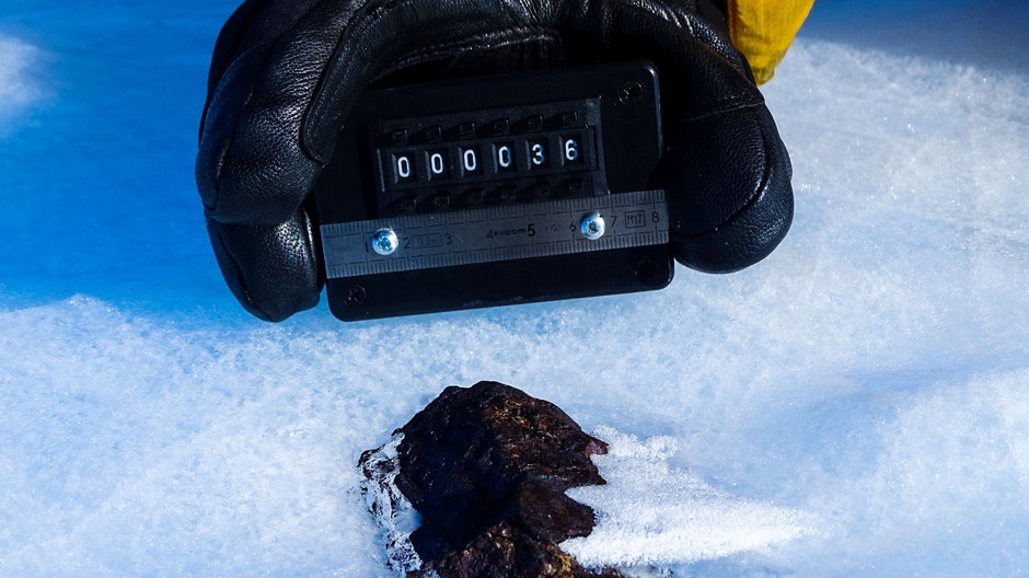Meteoryt HUT18036 częściowo zagłębiony w lodzie. Większość meteorytów zbierana jest z powierzchni