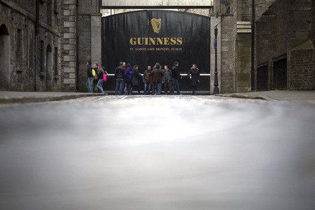 Dublin, Irlandia. Na zdjęciu: przechodnie i turyści przed bramą browaru Guinness St. James's Gate Brewery, należącego do Diageo Plc.