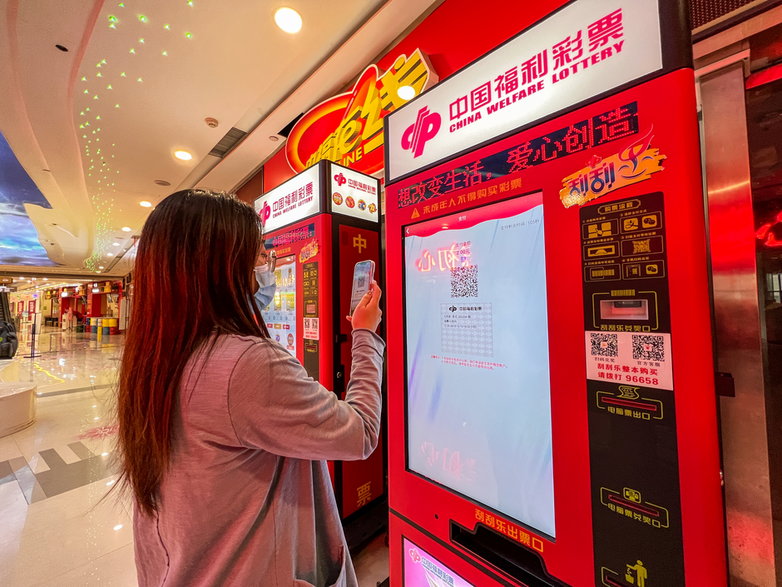 Kobieta kupuje los w automacie China Welfare Lottery w Zhengzhou 14 kwietnia 2022 r.