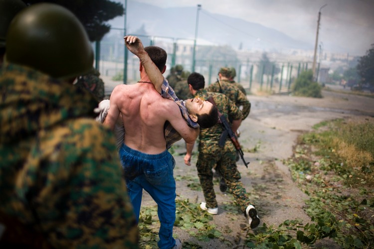 Mieszkaniec Gori niesie zwłoki zabitego przez Rosyjskie lotnictwo