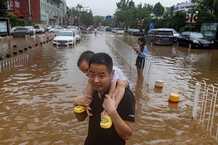 Mężczyzna z dzieckiem na rękach na ulicach Pekinu, 1 sierpnia 2023 r.