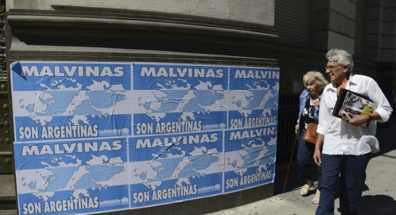 People walk past posters that read 'The Malvinas (Falklands Islands) are Argentine' in downtown Buenos Aires, on March 31, 2016