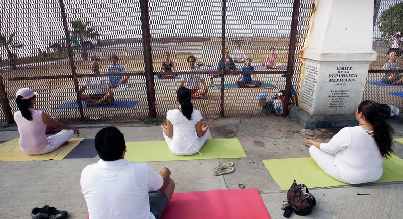 In this Sunday, June 22, 2008 photo, residents practice yoga on both sides of the U.S.-Mexico border fence as they take part in the Yoga without borders encounter in Tijuana, Mexico.