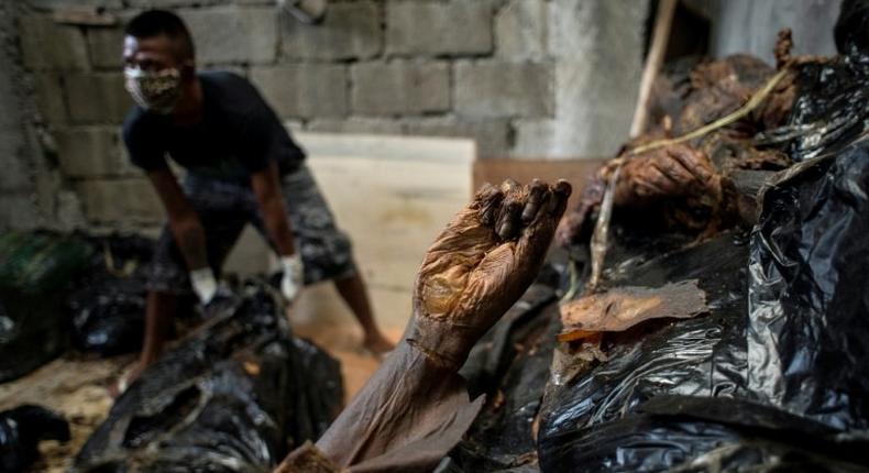 A worker arranges bodies in various stages of decomposition at the morgue of Henry's Funeral Homes in Manila