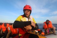 Spanish rescuer Daniel Calvelo carries a four-day-old baby girl into a RHIB, during a search and rescue operation by Spanish NGO Proactiva Open Arms, in central Mediterranean Sea, some 22 nautical miles north of the Libyan town of Sabratha