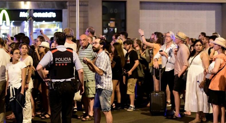 Tourists wait for the police to allow them to come back to their hotel on Las Ramblas boulevard after a van ploughed into the crowd, killing at least 13 people and injuring around 100 others on the Rambla in Barcelona, on August 18, 2017