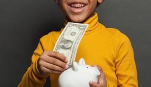 Stock image of a boy with a dollar bill.JNemchinova | Getty Images