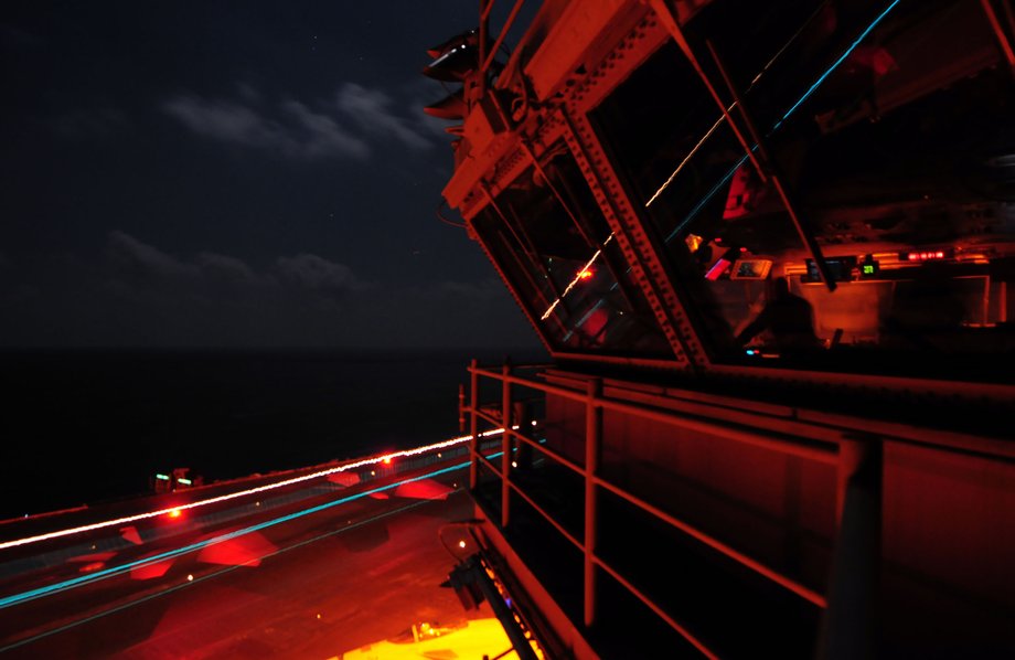 Sailors observe from the primary flight-control tower as an F/A-18 Hornet lands aboard the aircraft carrier USS Ronald Reagan.