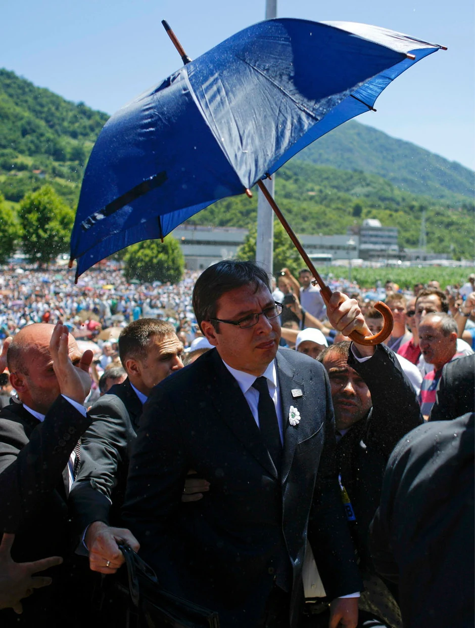 Vučića izvode s komemoracija štiteći ga kišobranom