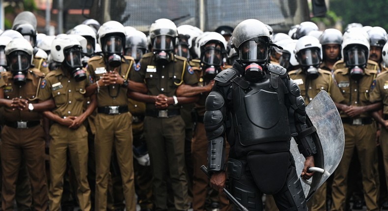 Policemen stand guard as university students and demonstrators protest in Colombo against the Sri Lankan government.