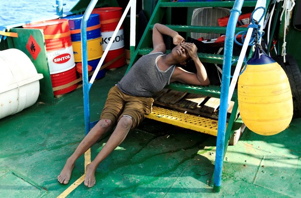 An exhausted migrant is seen onboard of Iuventa vessel after she was rescued from an overcrowded din