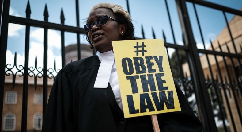 Kenyan lawyer and Law Society of Kenya's CEO Mercy Wambua holds a placard in front of the Supreme Court in Nairobi, on February 15, 2018 during a demonstration against impunity and disobedience of court orders. Kenya's Chief Justice on February 7 criticised the government for defying a number of court orders which he said placed the rule of law under threat, after a High Court ruling suspending the government's order for a broadcasting shutdown, which it found arbitrary and repressive, had been ignored. / AFP PHOTO / Yasuyoshi CHIBA (Photo credit should read YASUYOSHI CHIBA/AFP via Getty Images)