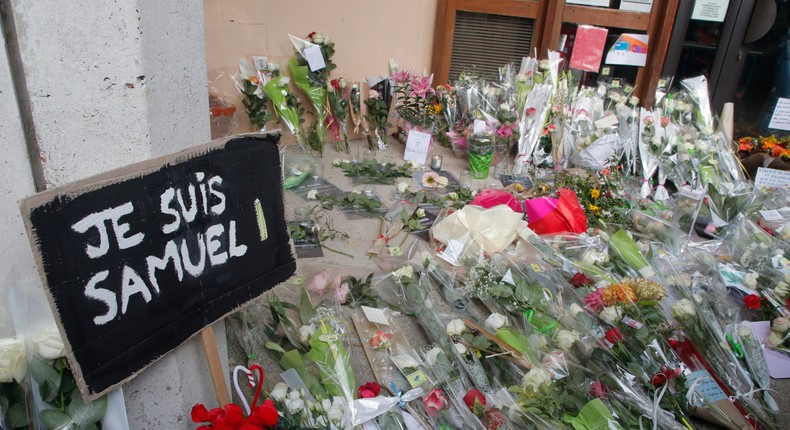 In this Oct.17, 2020 file photo, a poster reading I am Samuel and flowers lay outside the school where slain history teacher Samuel Paty was working.AP Photo/Michel Euler, File