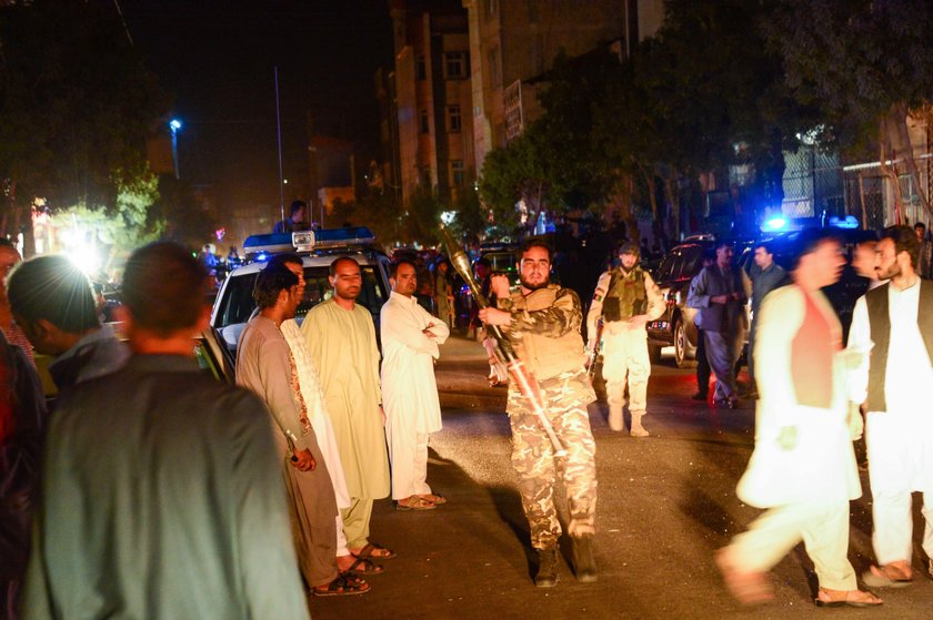 Afghan policemen and relatives inspect at the site of a suicide attack in Herat, Afghanistan