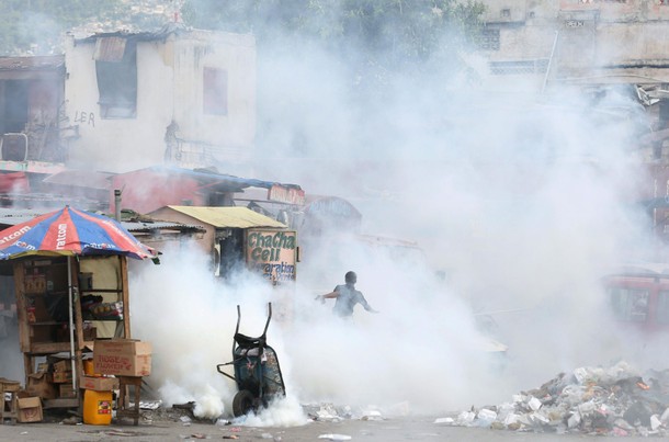 A man runs from tear gas during a protest against tax hikes, in Port-au-Prince