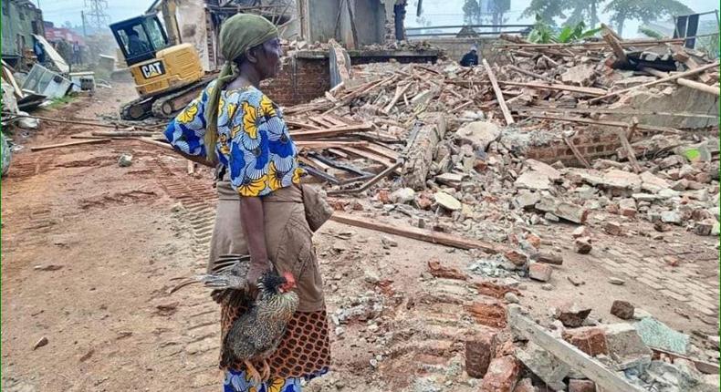 A woman stands over what was left of her house after the NEMA operation