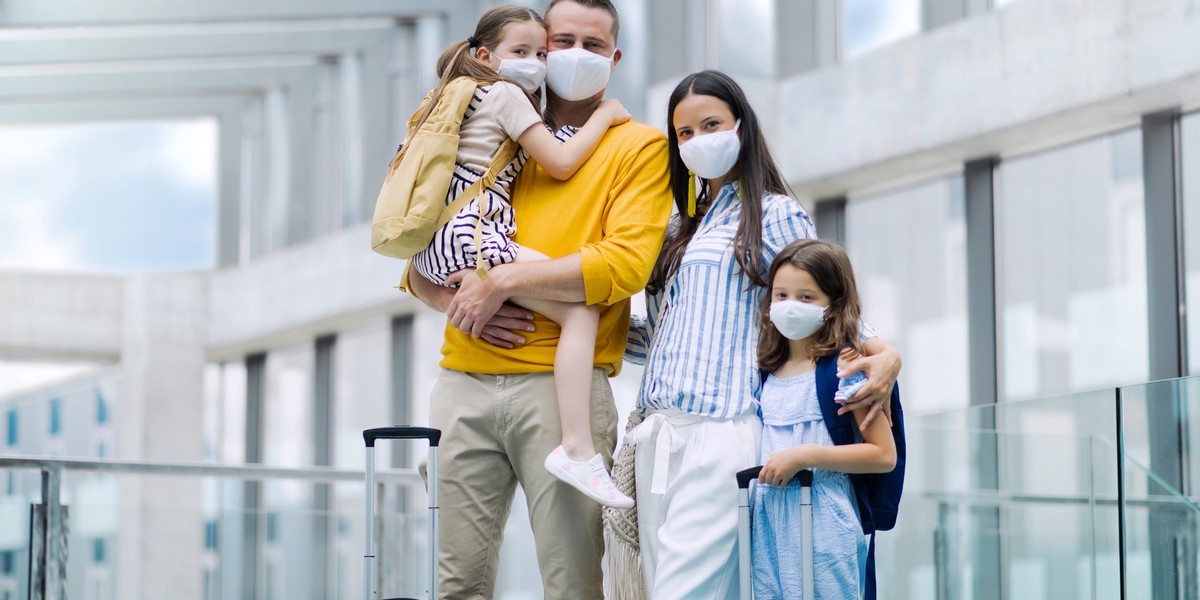 Family with two children going on holiday, wearing face masks at the airport.