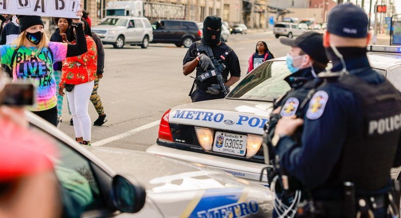 A protester holding a placard expressing her opinion in front of police during a memorial march from Jefferson Square Park to mark the one year anniversary since the Louisville Metro Police Department shot and killed Breonna Taylor at her home in Louisville.