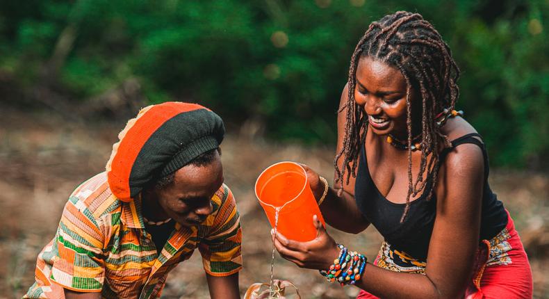 Couple watering a plant together. Photo by Safari Consoler
