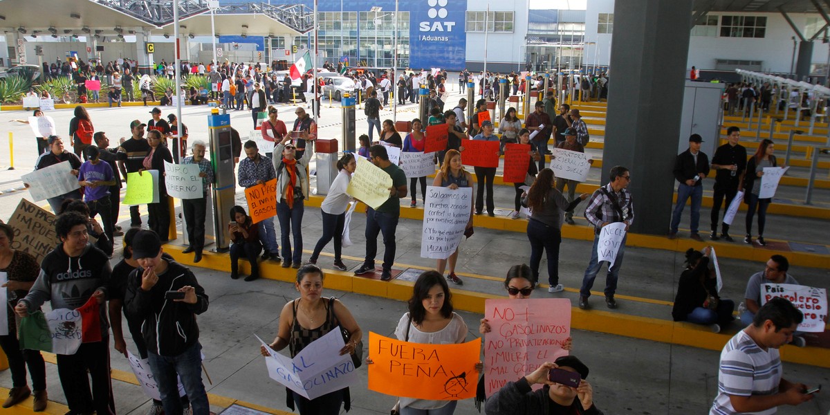 Demonstrators hold signs as they allow duty-free access for vehicles during a protest against the rising prices of gasoline enforced by the Mexican government in El Chaparral, on the border crossing between the US and Mexico, in Tijuana, Mexico, January 8, 2017.