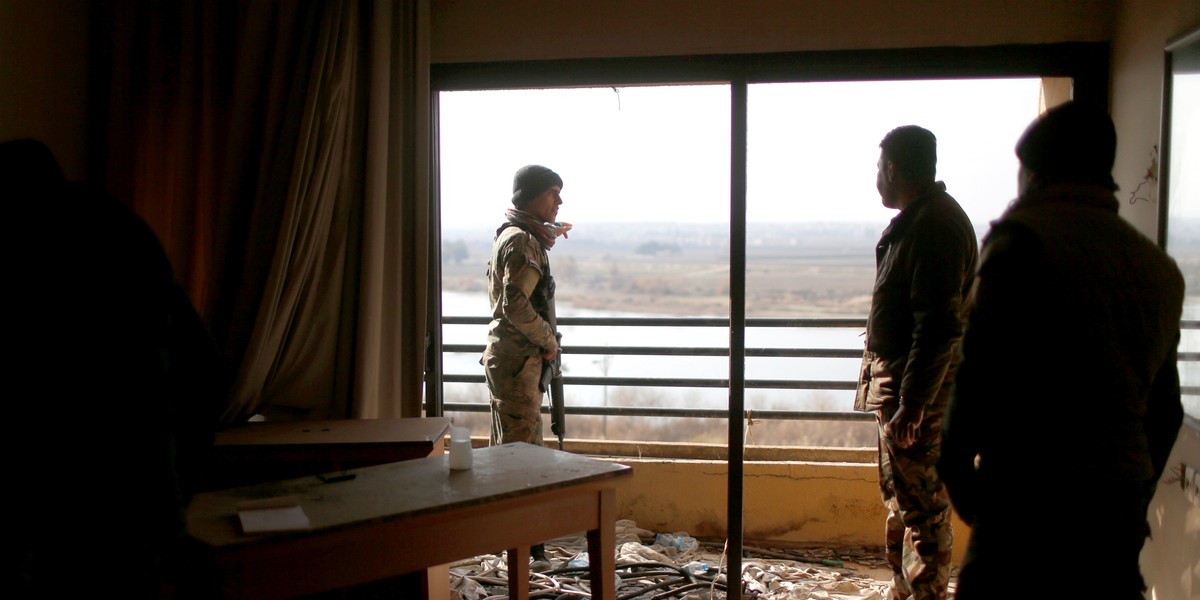 Iraqi soldiers looking out from a damaged room in the Ninewah Oberoi Hotel in Mosul.