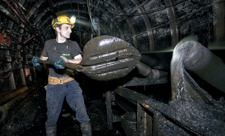 Górnik ładujący węgiel na taśmę transportową w kopalni w Jaworznie. Tauron jest właścicielem kopalni.