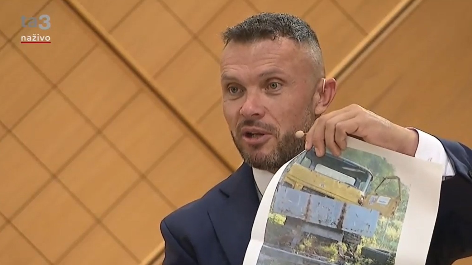 Miroslav Suja ukazuje v TA3 obrázky cestárskej techniky počas diskusie pred župnými voľbami na jeseň 2022. Župná akciovka, v ktorej vedení bol, desiatky strojov predala v roku 2017  za euro.