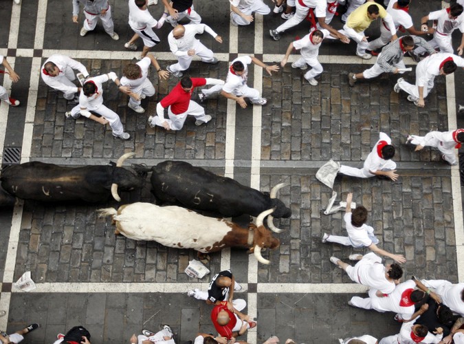 Uczestnicy fiesty w Pampelunie uciekają przed bykami.