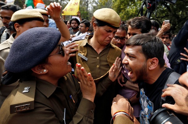 A protestor and police officer react during a march held on campus against violence and intimidation