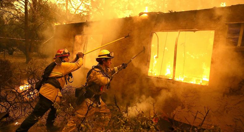 Firefighters try to keep flames from a burning home from spreading to a neighboring apartment complex as they battle the Camp Fire on November 9, 2018 in Paradise, California.