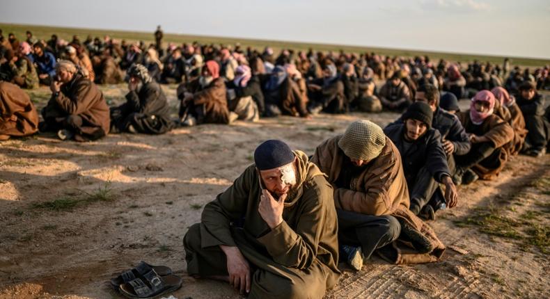 Suspected Islamic State group fighters wait to be searched after leaving the jihadists' last holdout in eastern Syria