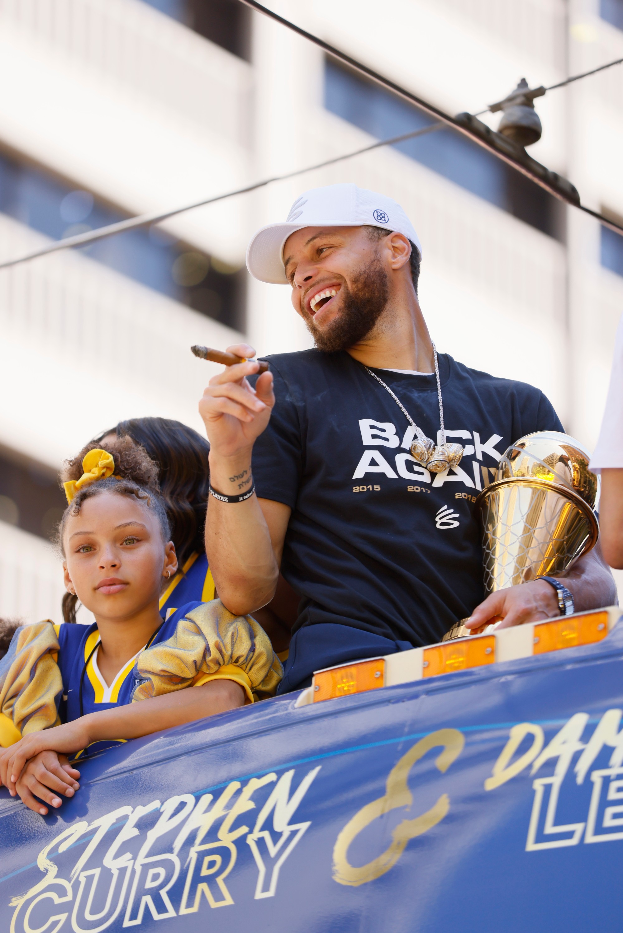 Basketbalista Golden State Warriors Stephen Curry (uprostred) oslavuje s trofejou zisk titulu v zámorskej NBA v uliciach San Francisca v pondelok 20. júna 2022.