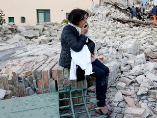 A woman sits amongst rubble following a quake in Amatrice