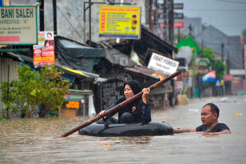 A man looks at a car damaged by the flood at a residential area in Bekasi