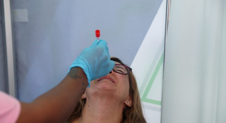 A healthcare worker collects a swab from Bronwen Cook for a PCR test against the coronavirus disease (COVID-19) before traveling to London, at O.R. Tambo International Airport in Johannesburg, South Africa, on November 26, 2021.