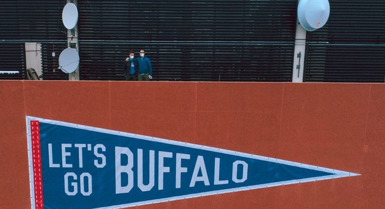 Brett Mikoll and Dave Horesh, the cofounders of Oxford Pennant, standing above their new banners hanging on Buffalo's Seneca One tower.