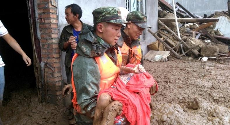 Rescuers carry a survivor of the landslide at Puge