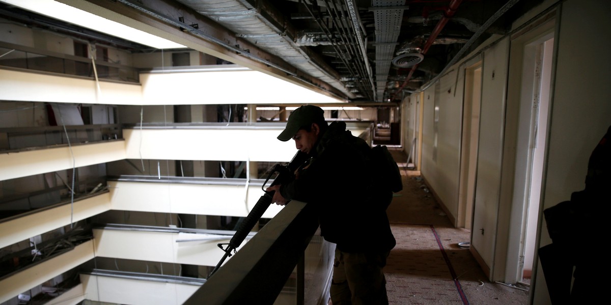 An Iraqi soldier holds his weapon while looking over a balcony in the Ninewah Oberoi Hotel in Mosul.